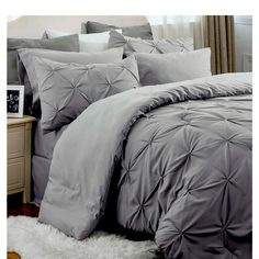 a bed with grey comforters and pillows