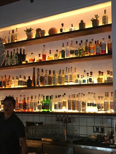 a man standing in front of a bar filled with liquor bottles