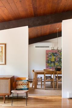 a living room filled with furniture and a painting on the wall above a wooden table