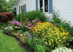 colorful flowers line the side of a white house