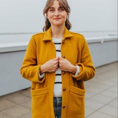 a woman wearing a yellow coat and jeans