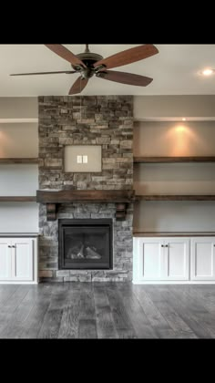 an empty living room with a fireplace and ceiling fan