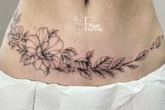 a woman's stomach with flowers and leaves tattoo on her side ribcage