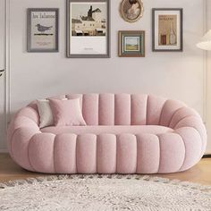 a living room with a pink couch and pictures on the wall above it, along with a white rug