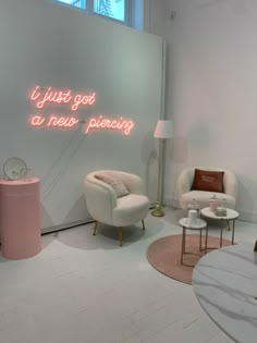 two chairs and a table in a room with a neon sign on the wall behind them