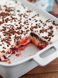 a dessert dish with white frosting and strawberries in it on a wooden table