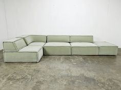 a white couch sitting on top of a cement floor next to a wall in an empty room