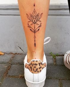 a woman's foot with a flower tattoo on her left leg and an animal print shoelace