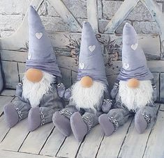 three stuffed gnomes sitting on top of a wooden bench