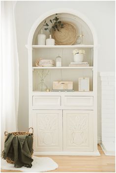 a white bookcase with baskets and other items on it