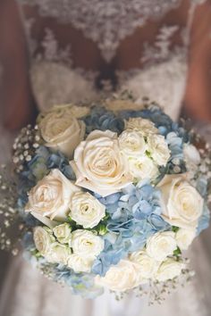 a bridal holding a bouquet of white roses and blue hydrangeas in her hands