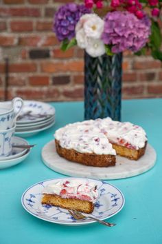 a piece of cake sitting on top of two plates next to a vase with flowers