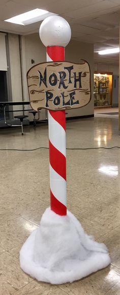 a pole with a sign that says north pole on it in the middle of a building