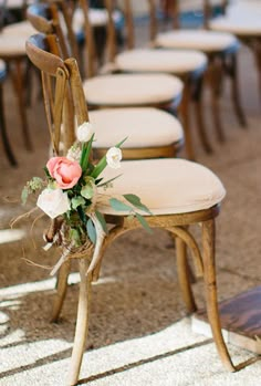 a row of wooden chairs with flower arrangements on the back and seat covers, all lined up in rows