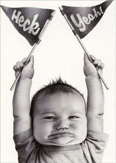 a black and white photo of a baby holding two flags with the words hey yeah on them