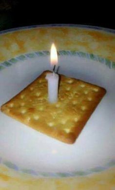 a cracker with a lit candle in it sitting on a white and yellow plate