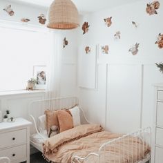 a bedroom with a bed, dressers and drawers in the corner that has butterflies on the wall