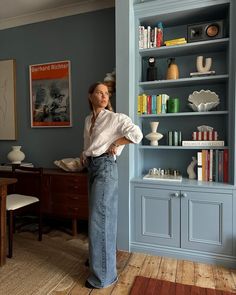 a woman standing in front of a blue bookcase