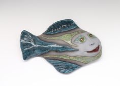 a ceramic fish with green eyes on it's side