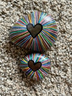 two heart shaped pins sitting on top of a carpeted floor next to each other