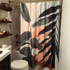 a bathroom with a toilet, shower curtain and shelves on the wall next to it