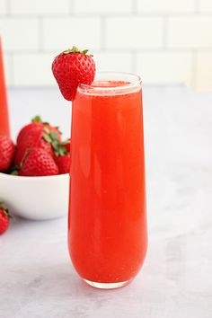 a glass filled with liquid next to some strawberries