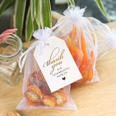 small bags filled with cookies sitting on top of a table next to a potted plant