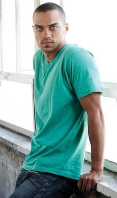 a man in a green shirt leaning against a window sill