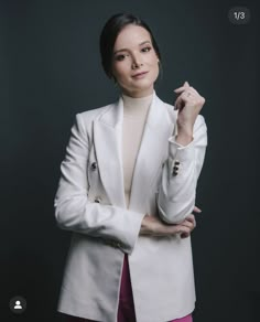 a woman in a white jacket and pink pants posing for the camera with her arms crossed