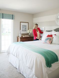 a woman standing on the edge of a bed in a room with white walls and carpet