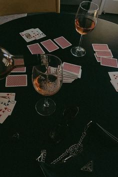 a table topped with cards next to a glass of wine on top of a table