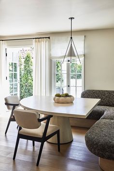 an image of a dining room setting with table and chairs in the foreground, couches on the other side