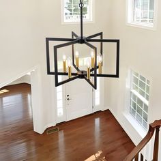 a chandelier hanging from the ceiling in a room with hardwood floors and white walls