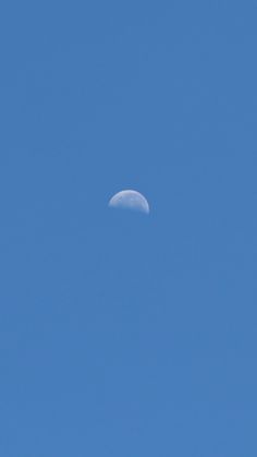 the moon is visible in the clear blue sky