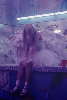 a woman sitting on top of a counter in front of a mirror with graffiti all over it