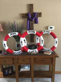 two life preservers sitting on top of a table next to a cross and potted plant