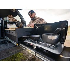 a man cooking food in the back of a truck