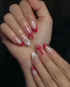 This almond-shaped nail design captures the essence of holiday joy with a blend of red glitter tips and intricate snowflake patterns. A standout feature is the accent nail adorned with a delicate red bow, reminiscent of a beautifully wrapped Christmas gift. The combination of white, red, and clear polish creates a look that is both festive and refined, perfect for any holiday gathering. Design Nails Christmas, Almond Shaped Nails Designs Christmas, Gel Polish Nail Designs White, Christmas Nails Elegant Red, Christmas Design Nail Art, Mistletoe Nails Christmas, Gift Wrap Nails, Almond French Tip Nails Christmas, Good Christmas Nails