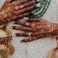 two hands with henna designs on them next to some decorative ornaments and bells,