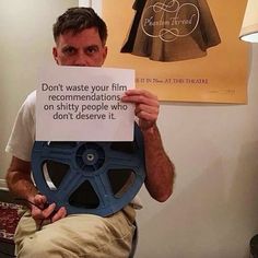 a man holding up a sign that reads don't waste your film recommendnations on utility people who don't observe it