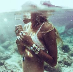 a woman standing under water holding a cell phone