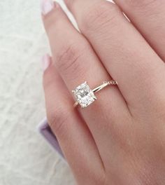 a woman's hand with a diamond ring on top of her finger and the other hand holding an engagement ring