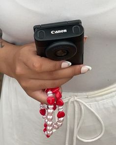 a woman holding a camera in her hand with beads on the strap around her wrist