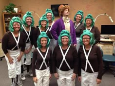 a group of people with green wigs and suspenders posing for a photo in an office