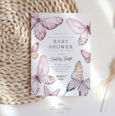 a baby shower card with butterflies on it next to a wicker basket and flowers