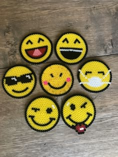 six embellished smiley face magnets sitting on top of a wooden table