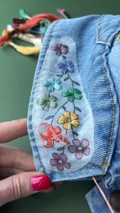 someone is stitching flowers on the back of their jean jacket