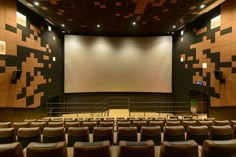 an empty auditorium with rows of seats and a projector screen on the wall behind it