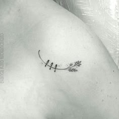 the back of a woman's shoulder with two birds sitting on a twig