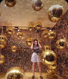 a woman is standing in front of some shiny balls and disco ball wallpapers